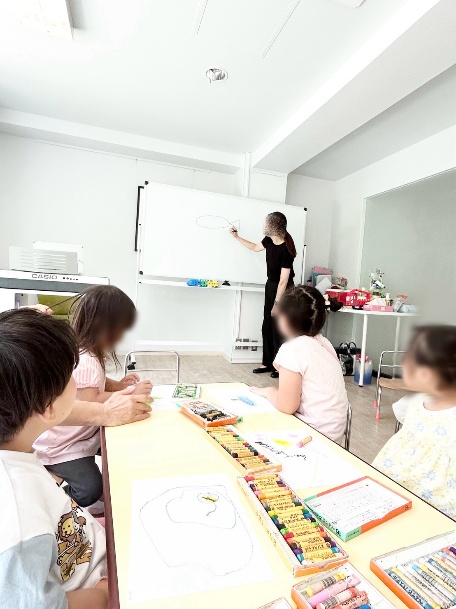 先生と一緒に机で課題に取り組む子どもたち
