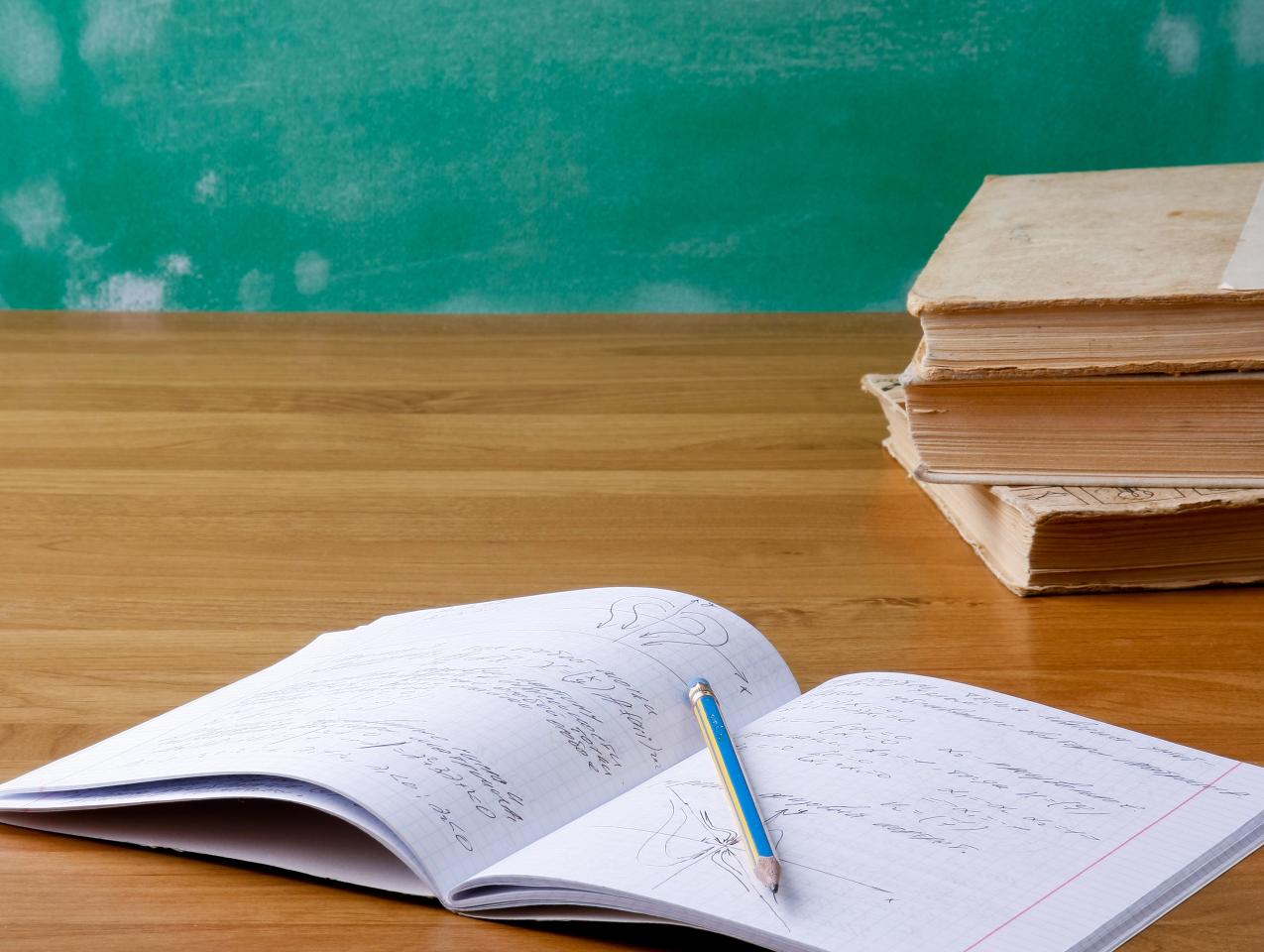 黒板と教科書、開いたノートと鉛筆のある学習机